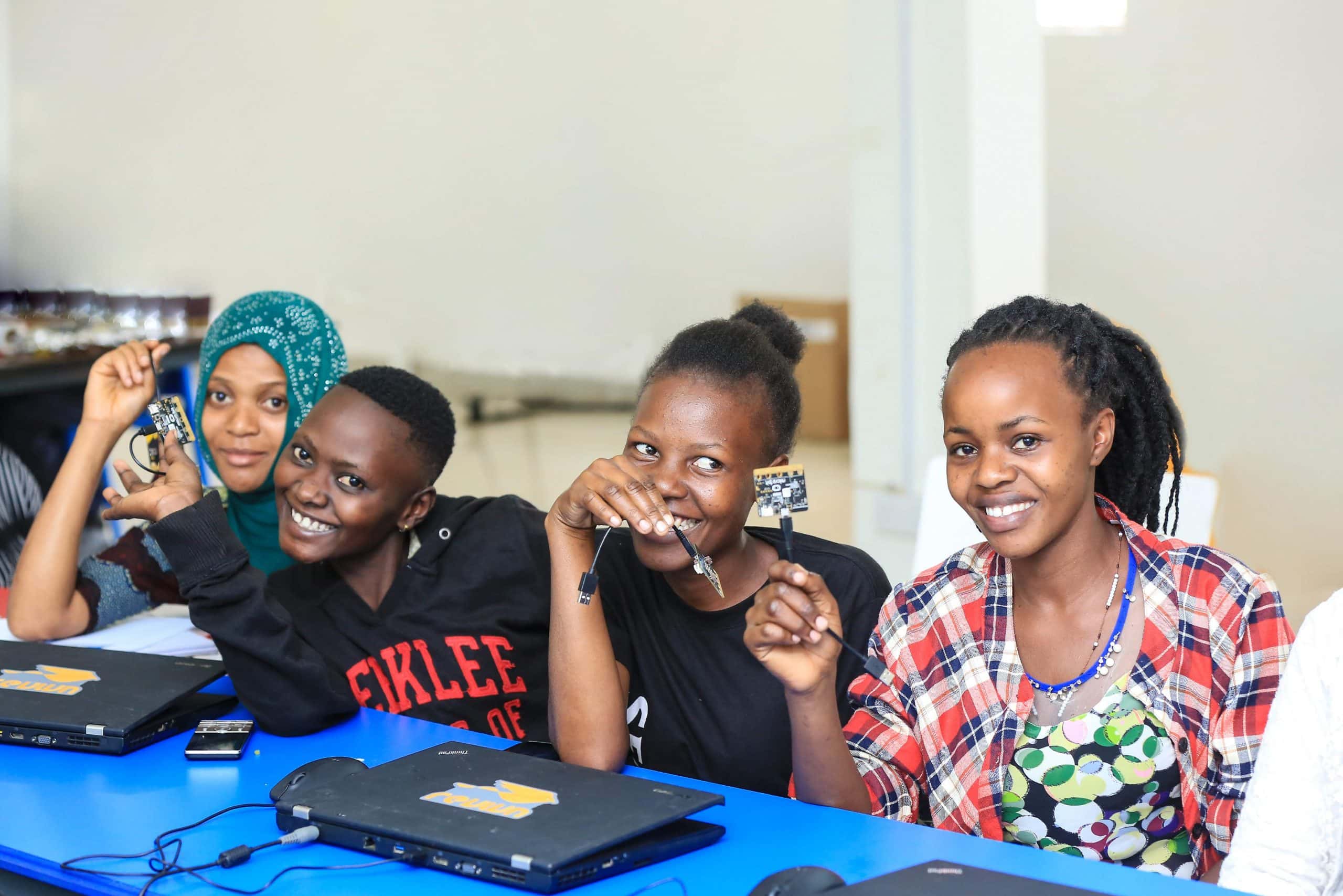 four women pose with computer hardware participating in technology skills for women in Uganda