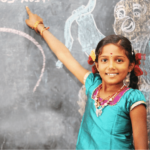 Girl smiling and pointing at artwork on chalk board
