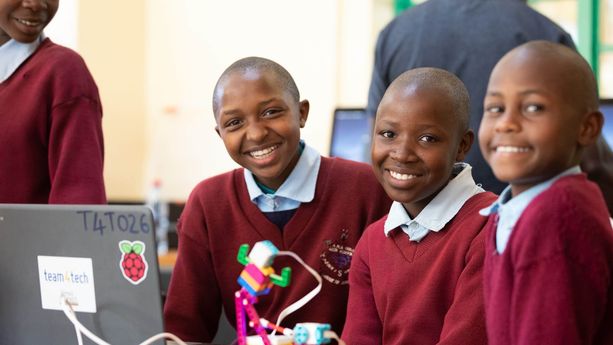Three young students working with educational resource partner Raspberry Pi Foundation on a computer provided with grant funds from Team4Tech
